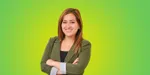 A lady with brown hair standing arms crossed in front of a green background.