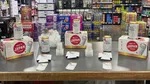 A Next Level tasting table set up with Suntory All-Free cans, six-packs, and sample cups in a beverage store.