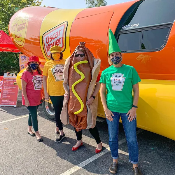 People dressed up as hot dog condiments in front of the Oscar Mayer WienerMobile.
